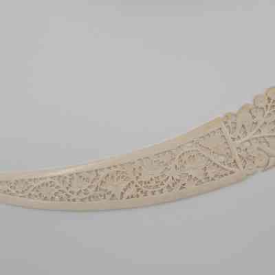 Large letter opener: The image displays an intricately carved ivory letter opener, featuring detailed designs of birds and floral patterns on the handle.