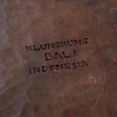 Bottom of the carved wooden figurine from Bali.: Up close image of the bottom of the carved wooden figurine. It is carved with the words "KLUNGKUNG BALI INDONESIA."
