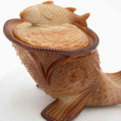 Brown Fish-Shaped Bowl: Close-up image of the fish-shaped bowl, focused on the cover. The fish bowl cover has detailed scales and has a brown tail. The fish bowl has a brown mouth with individual grooves etched into it.