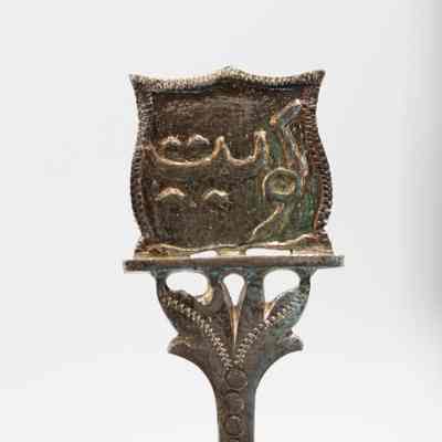 Arabic script on one of the spoon handles.: Up close image of one of the spoon handles with Arabic script. Under the text, the handle is decorated with debossed dots and engraved leaves.