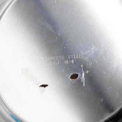 Bottom of the center bowl of the silver brazier.: Up close image of the bottom of the stainless steel bowl in the center of the brazier. It is engraved with  "STAINLESS STEEL S.K.J. 18-8."