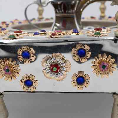 Stainless steel brazier gifted to Mrs. Jessie Jordan by Sheikh Sabah III Al-Salim Al-Sabah.: Up close image of the gold and gemstone flowers on the side of the stainless steel brazier.