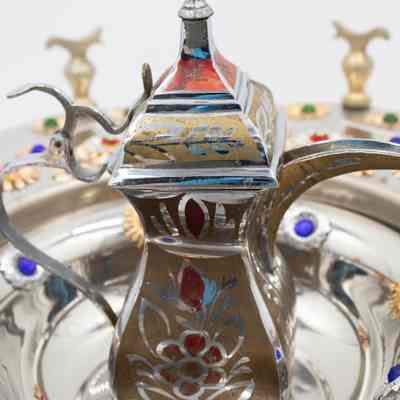 Stainless steel teapot from the brazier set.: Up close image of the stainless steel teapot decorated with a gold and red flower design.