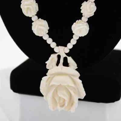 Carved ivory rose pendant: The ivory necklace features intricately engraved beads and a designed rose pendant.