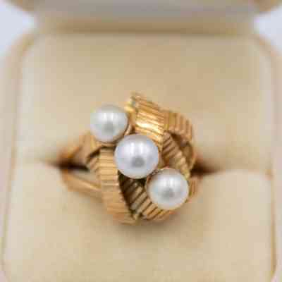 Gold knotted ring that belonged to Mrs. Jessie Jordan.: Up close image of the ring with a knotted gold design and three pearls in a diagonal in a white case.