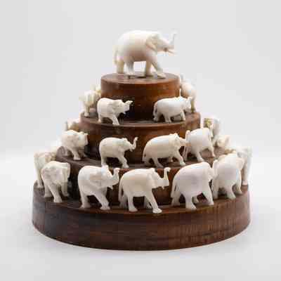Wooden "pyramid" with carved ivory elephants.: Image of the wooden pyramid with carved ivory elements. There are four steps and each contains less elephants than the one before. The largest elephants are on the bottom and top with slightly smaller ones on the middle two levels.