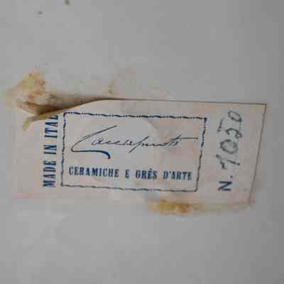 Sticker on bottom of figurine: A sticker that says “Made in Italy; Guido Cacciappuoti; Ceramiche E Grea D’arte; N. 1050”
