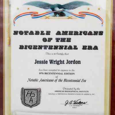Notable Americans of the Bicentennial Era Certificate: Close-up image of the certificate. A unfurled white scroll is depicted on the certificate and it is where the writing is contained in. The certificate reads "This is to Certify that Jessie Wright Jordan has been accepted to appear in the 1976 Bicentennial Edition of Notable Americans of the Bicentennial Era." This award was presented by the American Biographical Institute, a subsidiary of Historical Preservations of America, Inc. The Editor J.T. Vickers has signed it in a thick marker in the bottom right corner. In the bottom left corner is the logo of Historical Preservations of America, a black and white shield with leaves around it.
