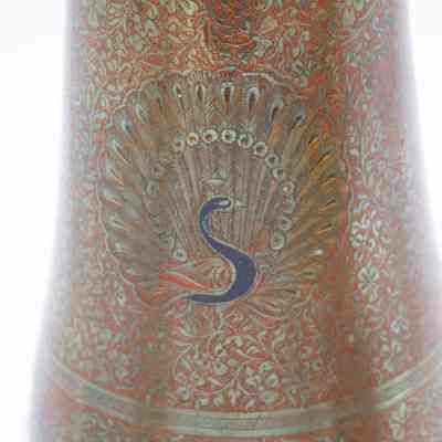 Peacock details: The brass vase features intricate floral engravings with a central peacock motif in vibrant colors.