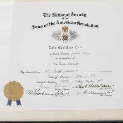 Sons of the American Revolution Membership Certificate: Close-up image of the certificate in its glass case. The President general, Secondary General, and the two State Presidents have signed their names on the certificate. The Sons of the American Revolution seal is gold with a blue ribbon.
