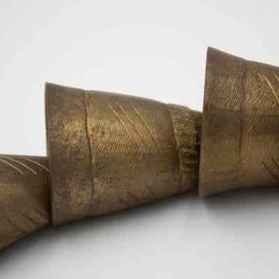 Camel bells: Nine brass camel bells hang in decreasing size, showcasing intricate designs and textures.