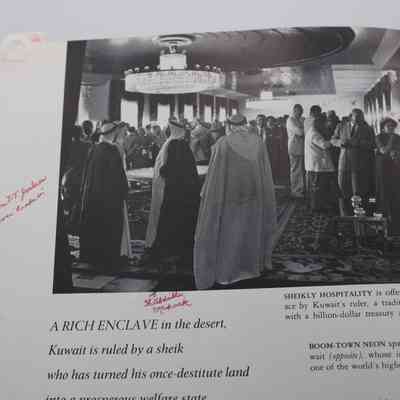 Banquet w/ Jordans Photograph Page with Notes: Inside "The Arab World” is a page which features a black and white photograph of a banquet held by the ruler of Kuwait. Handwritten notes in red ink are around the image. The first is a note that highlights the location of Mr. and Mrs. Jordan in the photo by referring to the X's written on the photo. On the right side of the photograph are Mr. and Mrs. Jordan talking with an Arabic dignitary, and the Jordans each have a red X over their heads. The second is a note that points an arrow to a specific Kuwaiti ruler.