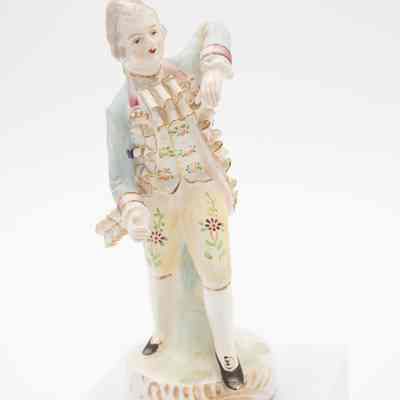 Painted porcelain figurine of a man.: Image of a painted porcelain figurine of a man dancing in colonial-style garments.