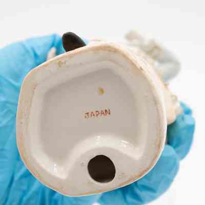 Bottom of the porcelain figurine of a man.: Up close image of the white bottom of the painted porcelain figurine of a man dancing. It is stamped with "JAPAN" in red letters.