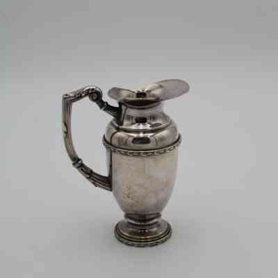 Silver creamer: A vintage silver creamer with intricate handle design.