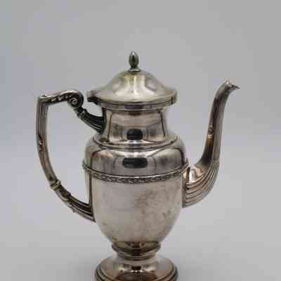Pitcher: The elegant silver creamer pitcher features intricate detailing and a gracefully curved handle and spout.
