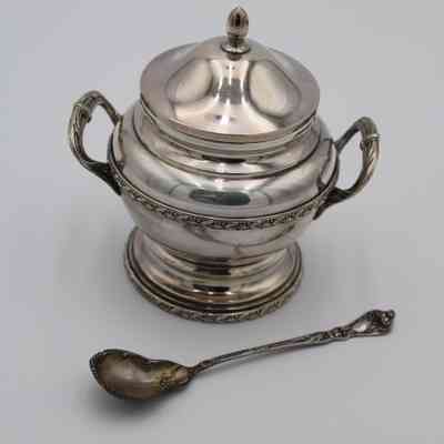 Sugar bowl and spoon: A silver sugar bowl with intricate handles and matching spoon on display.