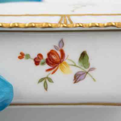 Side of the Royal Crown Derby cigarette box.: Up close image of one of the sides of the rectangular cigarette box. It is decorated with a red and purple flower with green leaves.