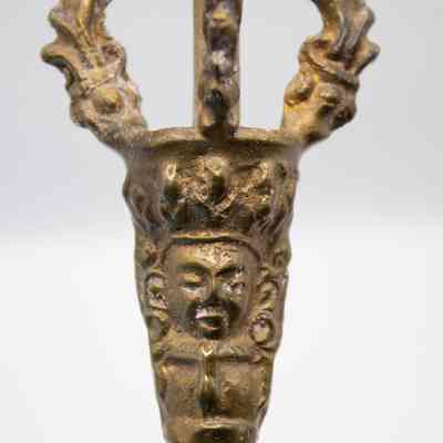 Bell handle: The brass Tibetan ritual prayer bell features a crown-shaped handle with intricate designs, including a face.