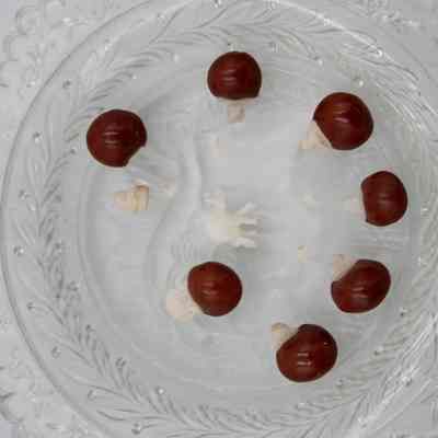 Seven lucky red seeds topped with miniature carved ivory elephants resting on a hexagonal crystal dish.: Image of the seven lucky red seeds topped with miniature carved ivory elephants resting on a hexagonal crystal dish. One of the small elephants has been detached and there is a small ivory elephant lying in the middle.