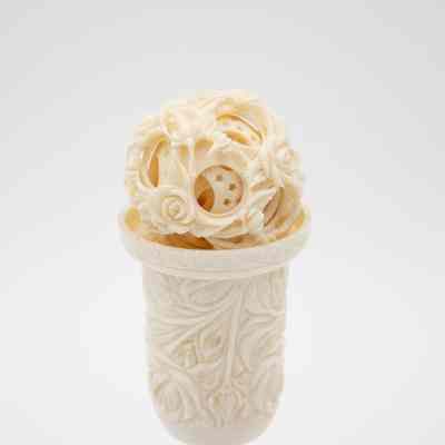 Carved ivory Chinese puzzle ball with pedestal.: Up close image of the carved ivory Chinese puzzle ball with pedestal. It is engraved with a floral rose design.