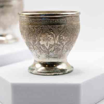 Silver goblet cup: A small Persian silver goblet cup features intricate engraved leaf designs.