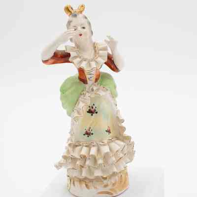 Painted porcelain figurine of a woman.: Image of a painted porcelain figurine of a woman dancing in colonial-style garments.