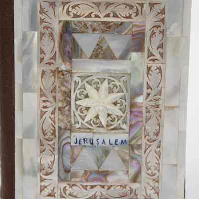 New Testament: The image displays a decorative piece with intricate mother-of-pearl inlay, including geometric and floral designs, featuring the word "Jerusalem."