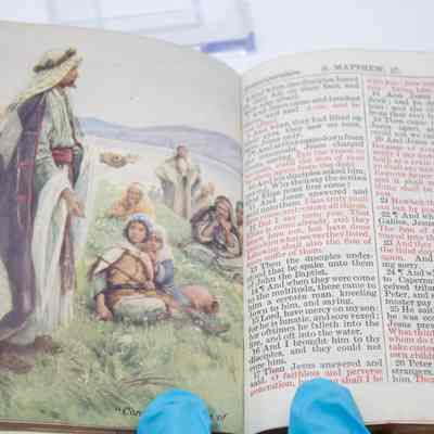 Inside of New Testament: An open New Testament shows an illustration on the left, depicting a biblical scene with figures, while the right page contains text from St. Matthew 17.