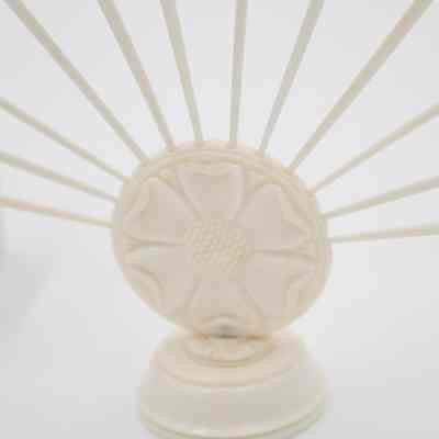 Base of one of the skewer sets.: Up close image of the base of one of the ivory bases. It depicts a flower.
