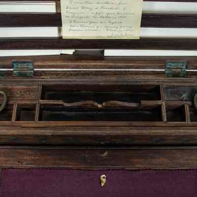 Inside of desk: The image shows an open, portable wooden secretaire from Venezuela, featuring compartments and a note inside.