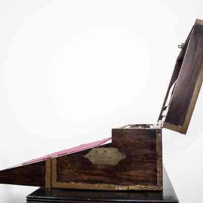 Side view of desk: The image showcases the side view of an open portable folding writing desk from Venezuela, made of ebony wood.