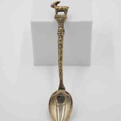 Singular Brass Capri Spoon: Photo of the spoon. The spoon has a lusterless brass finish, with mild weathering on its handle's design and goat motif. The word "CAPRI" is engraved on the handle, referring to a small island off the coast of Southern Italy famed for its natural beauty.