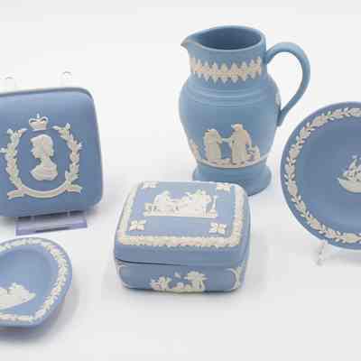 5 Wedgewood Jasperware blue dishes, all presented to Mrs. Jordan by the Queen at different times: 5 powder blue dishes. A box with a Queen Elizabeth profile, a pitcher with people, a heart shaped dish, a box with a scene of multiple people, and a plate with a ship.