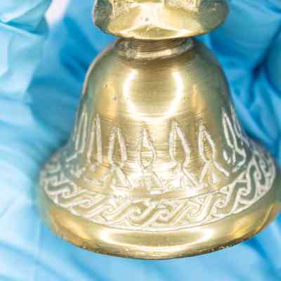 Close-up of bell: A close-up image of the engravements on the bell. It has a braided trim, then another trim with points.