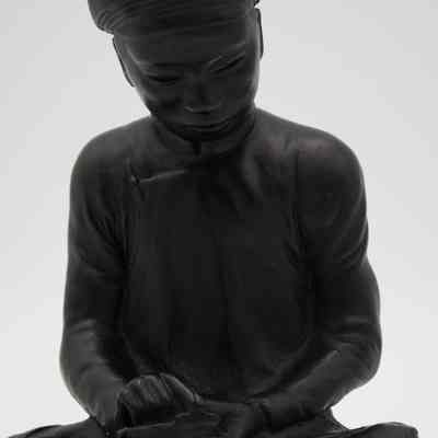 Cast statue of a man reading a book while seated.: Up close image of the black cast statue of a man reading a book while seated "crisscross." He is wearing a traditional Chinese garment and is wearing a round, pointed hat.
