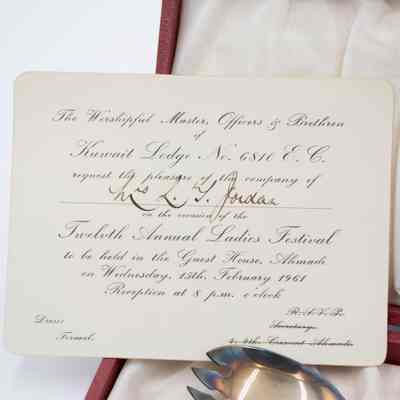 Invitation from the Ladies' Night where Mrs. Jessie Jordan received the set of silver salad spoons.: Up close image of the invitation from the Ladies' Night. The invitation reads "The Worshipful Master, Officers & Brethren of Kuwait Lodge No. 6810 E.C. request the pleasure of the company of Mrs. L.T. Jordan on the occasion of the Twelfth Annual Ladies Festival to be held in the Guest House, Ahmadi on Wednesday, 15th, February 1961 Reception at 8 p.m. o'clock." There is also small writing in the bottom corners, one reads" Dress: Formal" and the other "R.S.V.P. Secretary 4, 9th. Crescent Ahmadi."