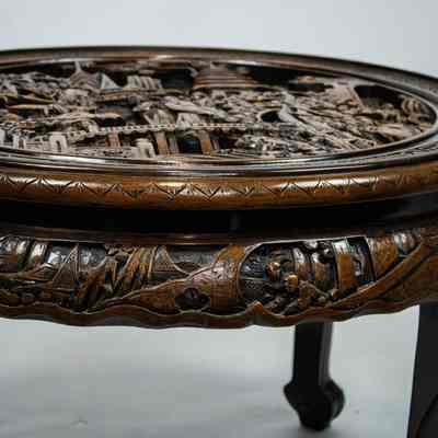 Round carved Hong Kong table: The intricately carved round table from Hong Kong features elaborate designs, topped with a protective glass surface.