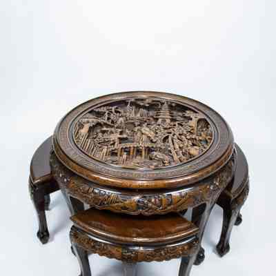 Round carved Hong Kong table and stools: The image shows a beautifully carved round Hong Kong table with a glass top, featuring intricate detailing and matching curved stools underneath.