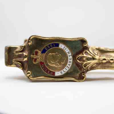 Close up of nutcracker: The image shows a detailed, gold handle with an emblem commemorating Queen Elizabeth II in 1953. It has a profile of Elizabeth and a crown.