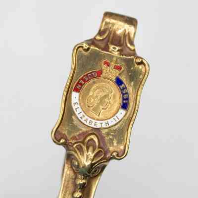 Close up of nutcracker: The image shows a detailed, gold handle with an emblem commemorating Queen Elizabeth II in 1953. It has a profile of Elizabeth and a crown.