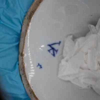 Bottom of the two-sided figurine: The bottom of the figurine is solid white but shows wear. Its edges are turning brown from age. There are small triangular blue marks likely indicating the creator of the doll.