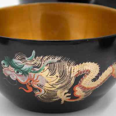 Outside of one of the soup bowls.: Up close image of the outside of one of 12 soup bowls painted with a green, red, and gold Chinese dragon.