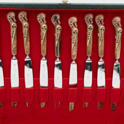 Knives in case: A set of seahorse-handled knives rests neatly in a red felt-lined case.