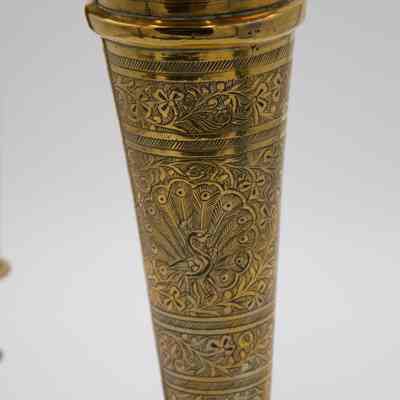 Peacock engraving: The tall brass vase features an intricate peacock design etched into its surface.