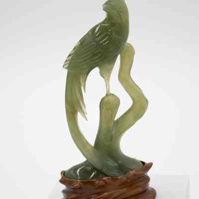 Carved jade bird statuette.: Image of one of the two carved jade bird statuettes on a mahogany wood base.