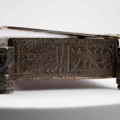 Cigarette box: The silver cigarette box features intricate Incan-style mythological engravings on its surface.