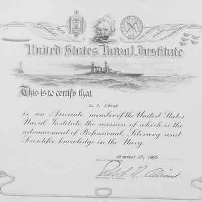 US Naval Institute Certificate: Close-up image of the certificate in the case. A depiction of a sailboat is at the top of the certificate with the depiction of a modern warship below the name of the institute. In cursive script it reads "This is to certify that L.T. Jordan is an Associate member of the United States Naval Institute, the mission of which is the advancement of Professional Literary and Scientific knowledge in the Navy." It is dated December 28, 1956. The Secretary-Treasurer Robert N. [illegible] has signed it.