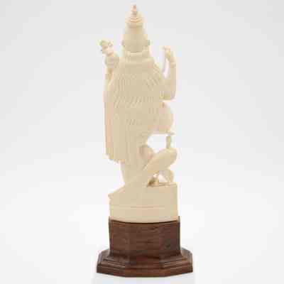Back of the carved ivory figure of Saraswati mounted on a wooden base from India.: Image of the back of a carved ivory figure of Saraswati. There is a peacock at her right foot and her hair is long down her back.