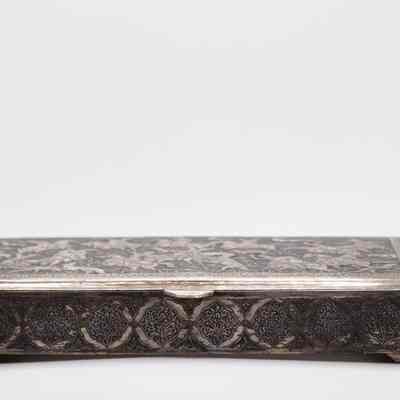 Side of the small chased silver box debossed with a hunting scene.: Image of the side of the rectangular silver box. The sides are engraved with a ghalam zani decoration of peony cartouches and arabesques.